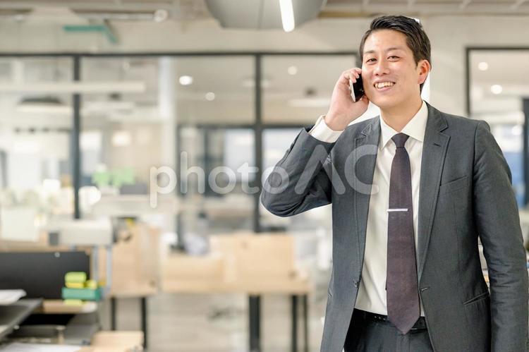 爽やかなビジネスマンとオフィス 電話,スマホ,笑顔の写真素材