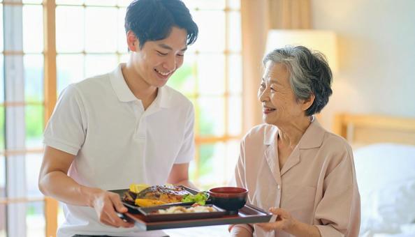 高齢女性と男性介護士の穏やかな食事風景 高齢女性と男性介護士の穏やかな食事風景の写真