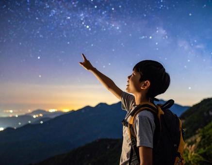満天の星空を指差し見上げる少年 満天の星空を指差し見上げる少年の写真
