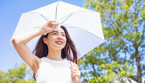 日傘をさして白いハンカチで汗を拭く女性 日傘をさして白いハンカチで汗を拭く女性の写真