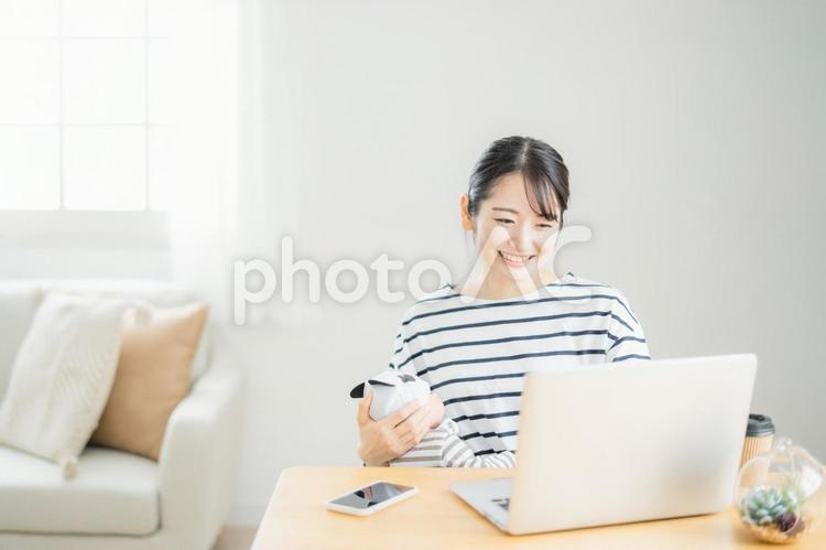 赤ちゃんを抱きながらパソコンを使う女性 育児休業,パソコン,在宅勤務の写真素材