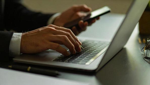 デスクワーク　パソコンに両手で入力するの写真