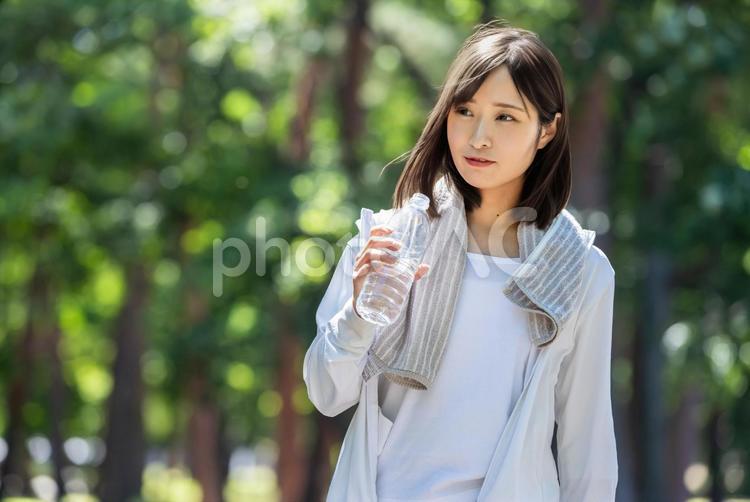 タオルで汗を拭って水分補給する女性 水分補給,有酸素運動,ペットボトルの写真素材
