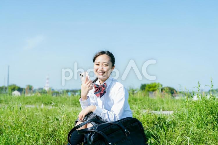 青空の下でスマホを持つ女子高校生 スマホ,高校生,女性の写真素材