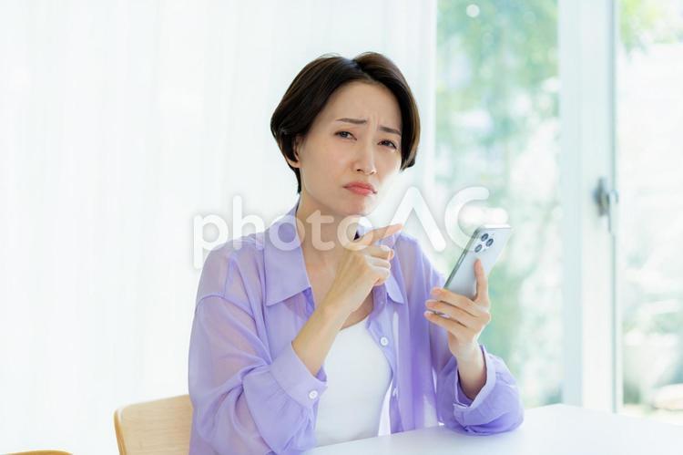 スマホを持って考える女性 スマホ,考える,悩むの写真素材