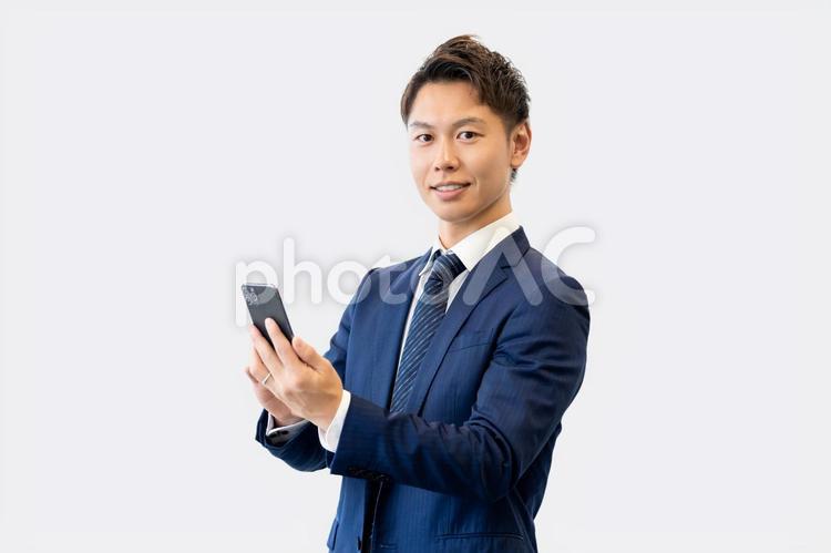 スマホを持つ笑顔の男性ビジネスマン 男性,スマホ,ビジネスの写真素材