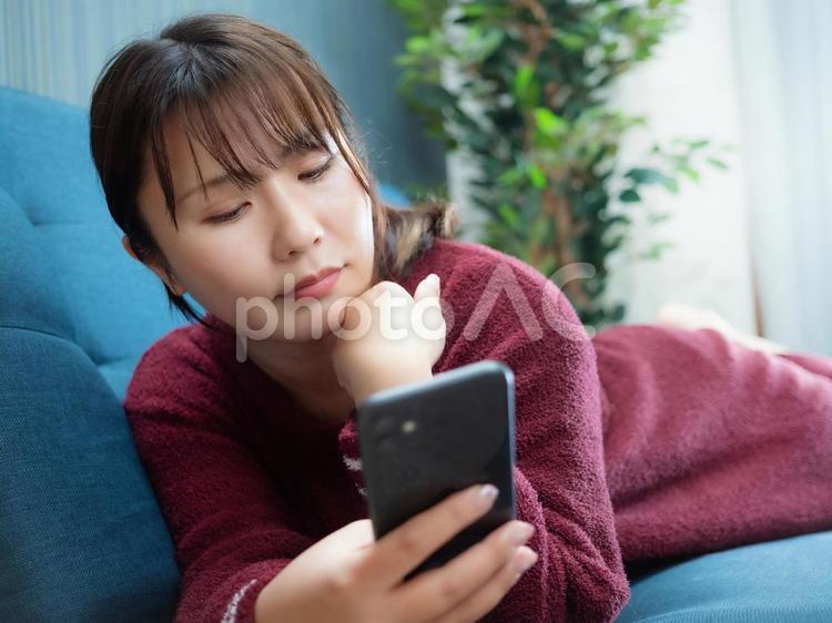 03：ソファーでスマホを操作する女性 スマホ,スマートフォン,電話の写真素材