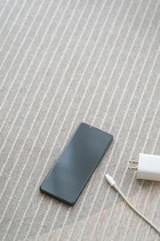 カーペットの上にスマホと充電コード カーペットの上にスマホと充電コードの写真