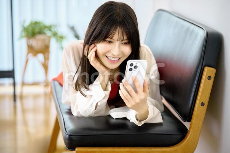 ソファでスマホ見る若い女性 スマホ,女性,ソファの写真素材