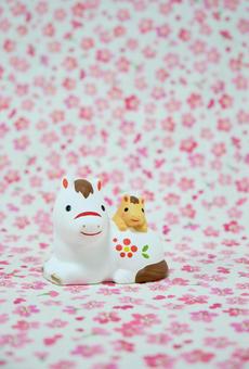 可愛い馬の置物と花柄の背景の年賀状素材の写真