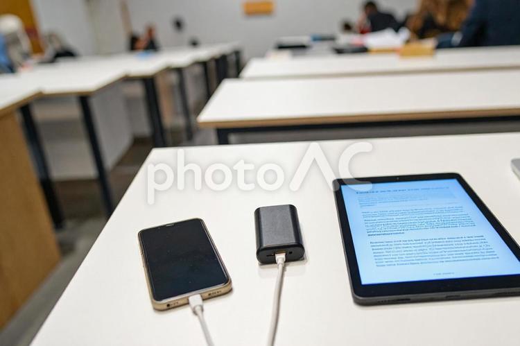 机の上に置かれた充電中のスマホ スマホ,スマートフォン,モバイルバッテリーの写真素材