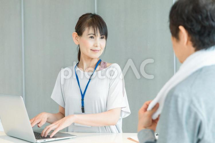 スポーツジムの受付をする女性（ノートパソコン） スポーツジム,体験入会,受付の写真素材