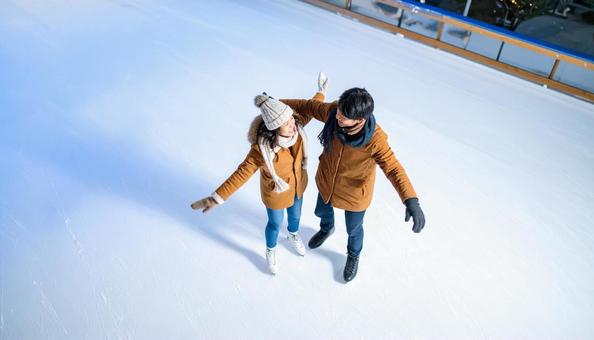 アイススケートリンクで滑るカップル アイススケートリンクで滑るカップルの写真
