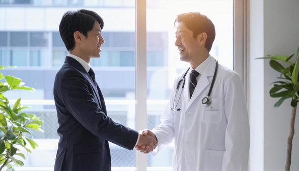 握手するビジネスパーソンと医者 握手するビジネスパーソンと医者の写真