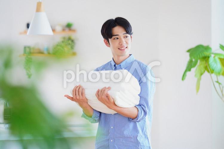 畳んだタオルを運ぶ笑顔の男性 男性,タオル,運ぶの写真素材
