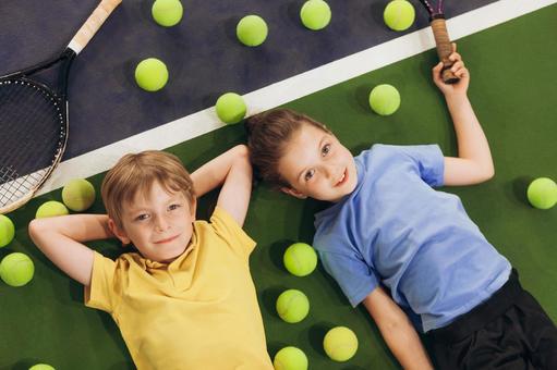 テニスボールに囲まれて寝転ぶ子供たち 男女,子供,外国人の写真素材