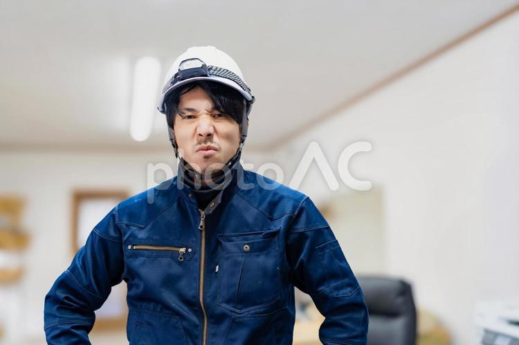 ヘルメットをかぶったしかめっ面の作業員 ビジネス,ビジネスマン,男の写真素材