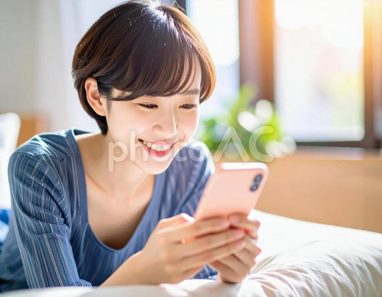 ソファでスマホを見る女性2 スマートフォン,スマホ,女性の写真素材