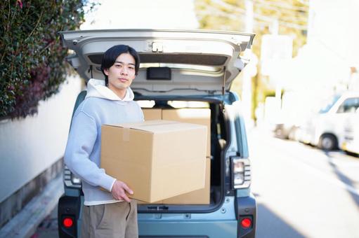 車から引っ越しの段ボール箱を運び出す男性 車から引っ越しの段ボール箱を運び出す男性 引っ越し,一人暮らし,男性の写真素材
