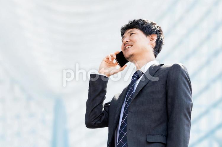スマホで通話をする笑顔の男性ビジネスマン 男性,スマホ,ビジネスの写真素材