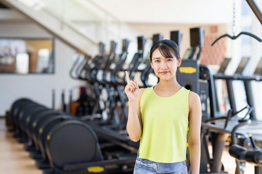 ジムでおすすめする若い女性 指差し,ジム,フィットネスの写真素材