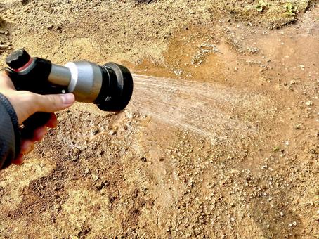 地面に散水ノズルで水まきするイメージ 地面に散水ノズルで水まきするイメージ 散水,ホース,散水ノズルの写真素材