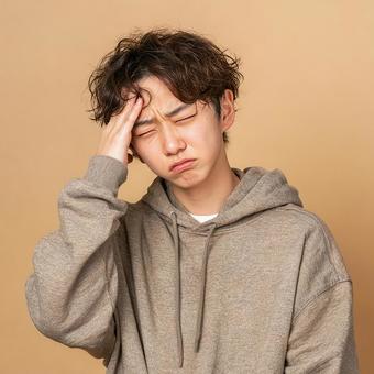 ベージュの背景で苦悩するアジア人男性 ベージュの背景で苦悩するアジア人男性の写真