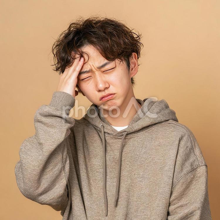 ベージュの背景で苦悩するアジア人男性 男性,若者,日本人の写真素材