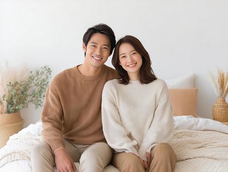 ベッドに座る笑顔の若いカップル ベッドに座る笑顔の若いカップルの写真