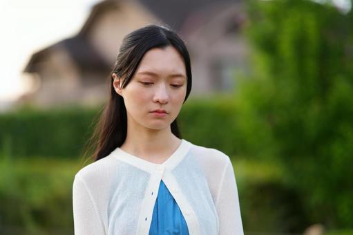 屋外で悲しい顔をするカーディガンの女性 女性,日本人,ショックの写真素材