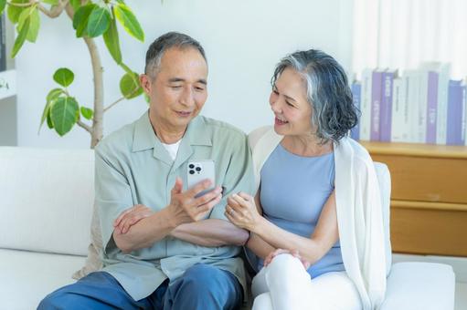 リビングでスマホを見るシニア夫婦 スマホ,シニア,笑顔の写真素材