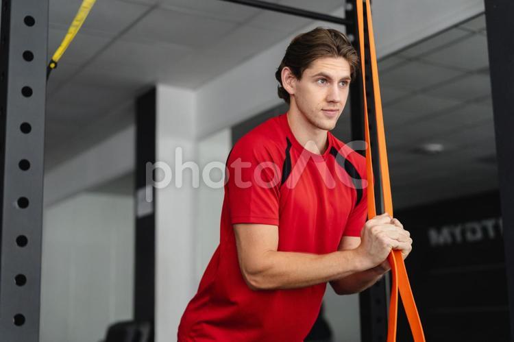 チューブトレーニングをする赤色のウェアの男性 トレーニング,ジム,筋トレの写真素材