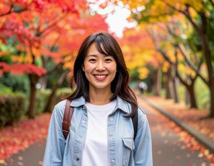 紅葉の道を散歩する女性 紅葉の道を散歩する女性の写真