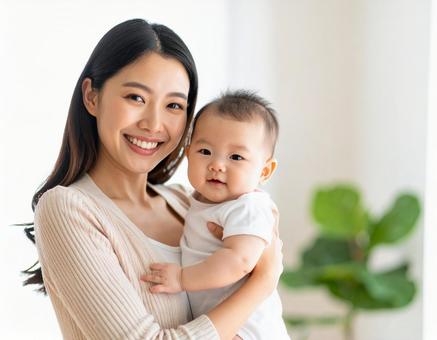赤ちゃんを抱いて微笑んでいる若いお母さん 赤ちゃんを抱いて微笑んでいる若いお母さんの写真