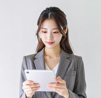 タブレットPCを確認する女性の写真