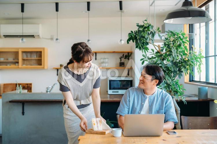 テレワークする男性と食事を運ぶ女性 ランチ,テレワーク,昼食の写真素材