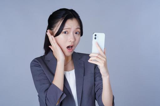 スマホを見て驚くスーツ姿の女性 女性,スマートフォン,持つの写真素材