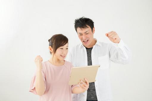 A man and a woman exciting when looking at a tablet A man and a woman exciting when looking at a tablet