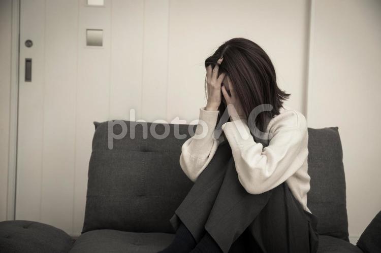 ソファーで頭を抱える女性　cry 女性,落ち込む,ショックの写真素材