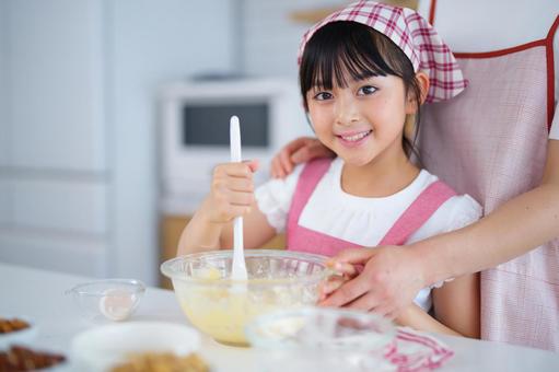 エプロン姿でお菓子作りを楽しむ親子 女の子,小学生,日本人の写真素材