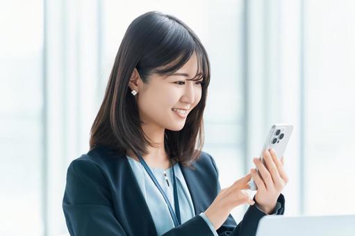 スマホを使う笑顔の女性・ビジネスウーマン スマホを使う笑顔の女性・ビジネスウーマン 女性,スマホ,スマートフォンの写真素材