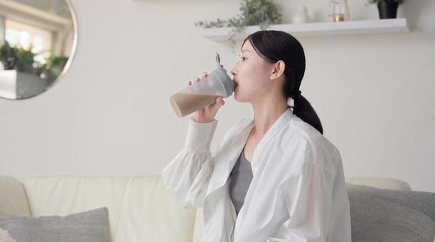 リビングでプロテインを飲むアジア人女性 プロテイン,飲む,女性の写真素材