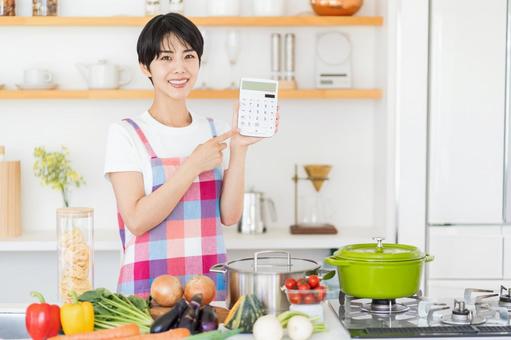 キッチンで電卓を持つ主婦。 キッチンで電卓を持つ主婦。の写真