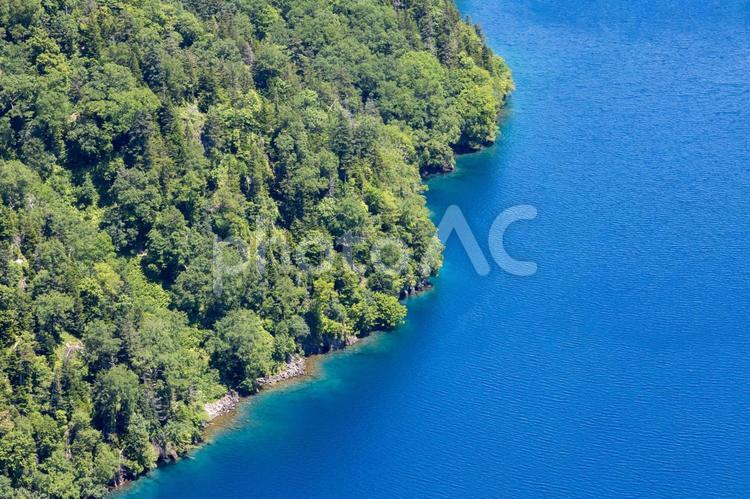 真っ青な摩周湖の水際と緑の木々 知床観光,カムイシュ島,道東の写真素材