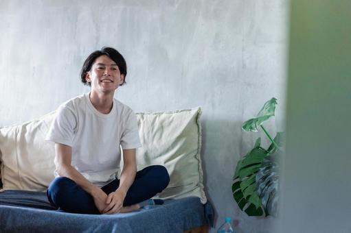 ベッドで伸びをする若い男性 ベッドで伸びをする若い男性の写真