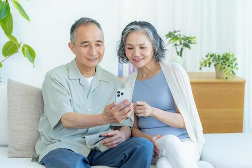 リビングでスマホを見るシニア夫婦 スマホ,シニア,笑顔の写真素材