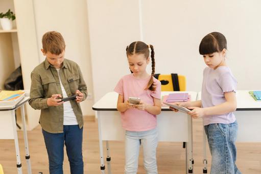携帯とタブレットを見ている生徒たち 男の子,女の子,子どもの写真素材