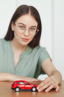 赤い車の模型に笑顔の女性スタッフ 保険業,事務職,接客業の写真素材