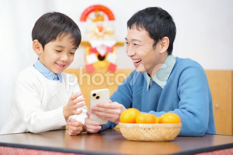 笑顔で男の子に携帯を見せる男性 親子,男性,男の子の写真素材