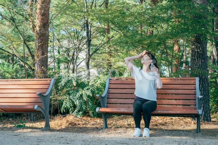 トレーニング中に休憩する女性（水を飲む・笑顔） 水分補給,汗,水の写真素材